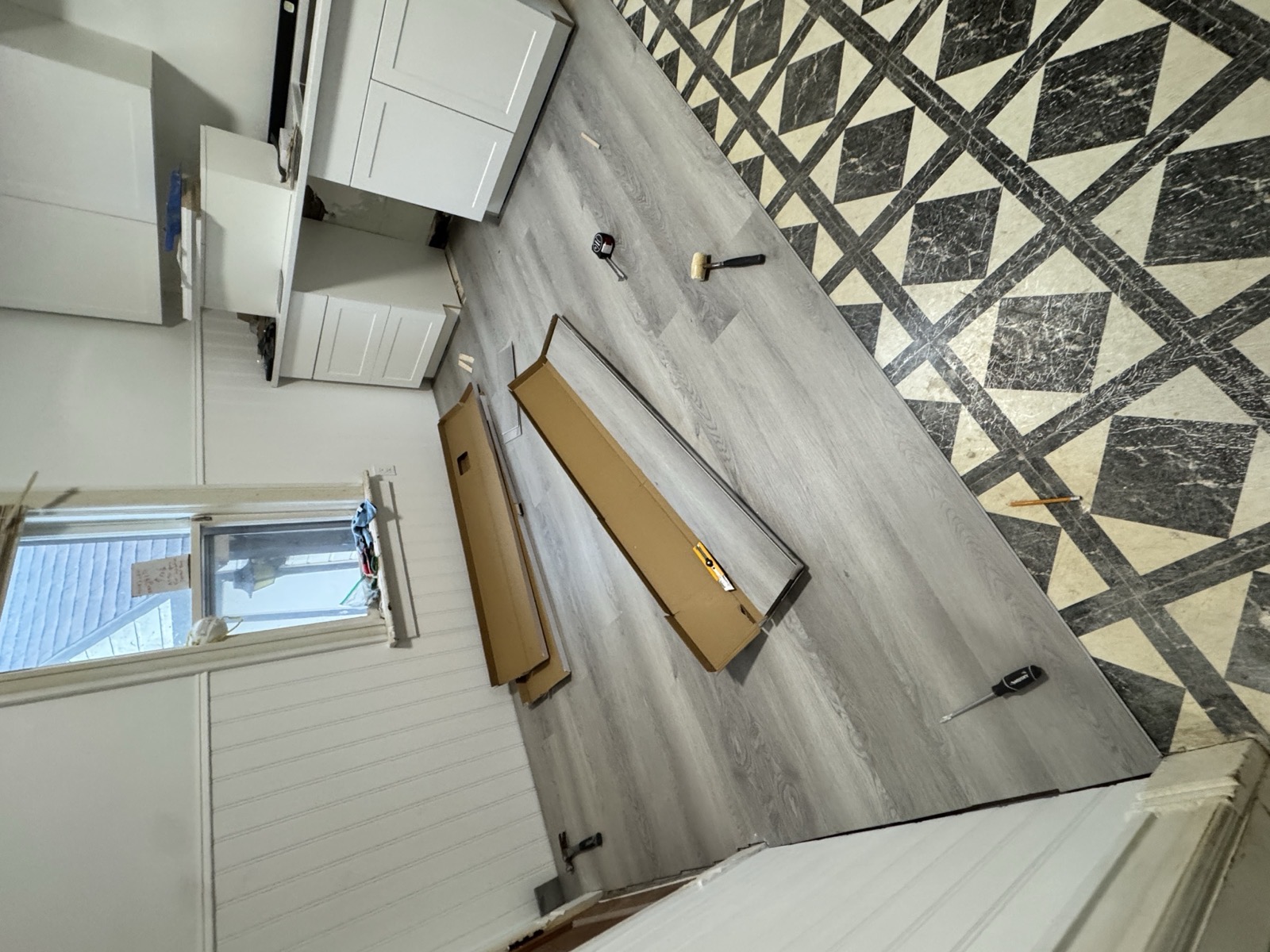 Plank flooring going down over old 1950s tile, half finished