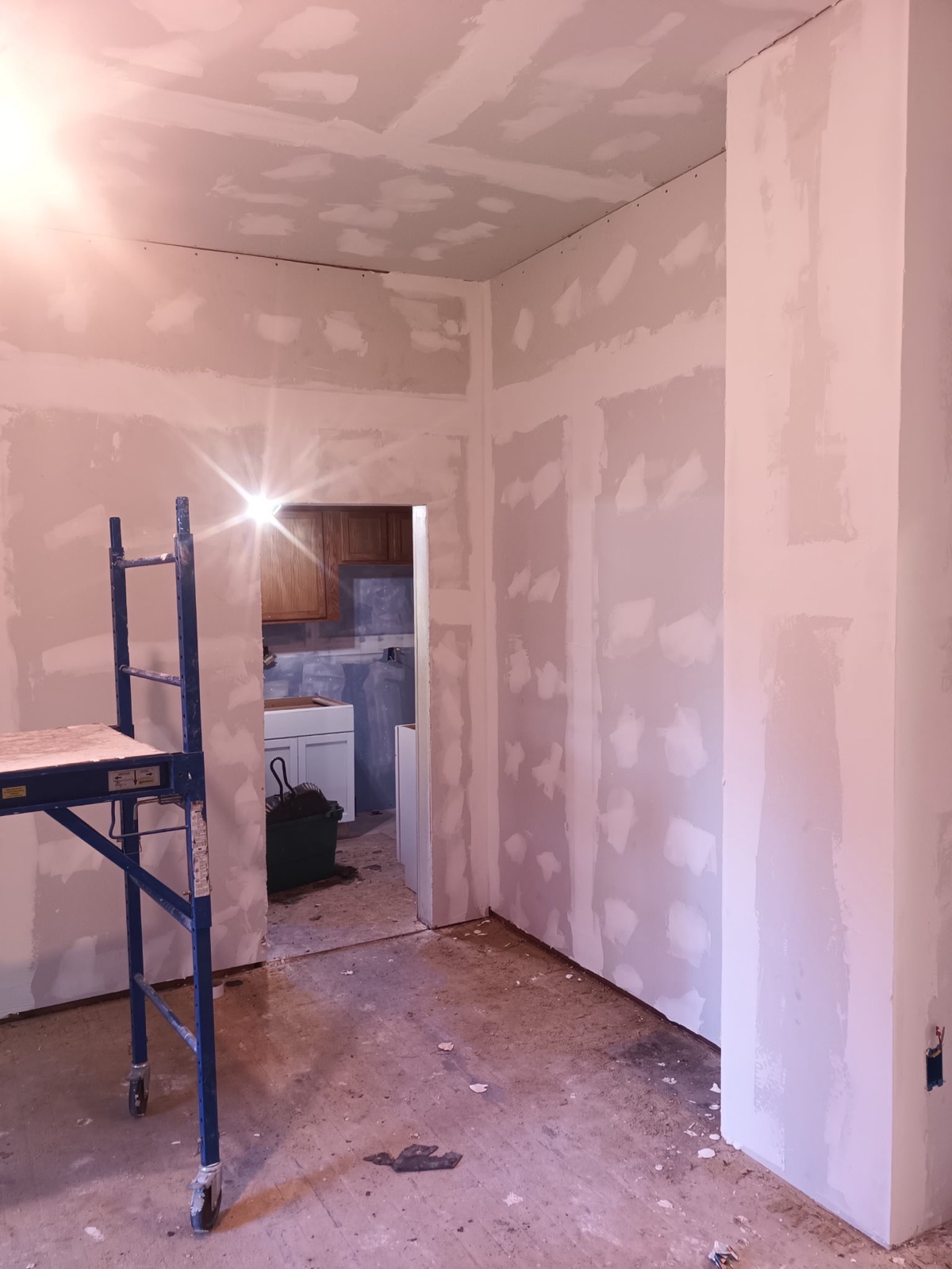 Drywall taped and mudded, scaffold still in the room